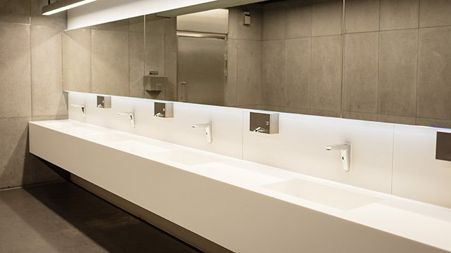 Hygienische und energieeffiziente Sanitärinstallation mit Sensorarmaturen Moderne Waschtischanlage mit berührungslosen Armaturen in einem öffentlichen Sanitärraum