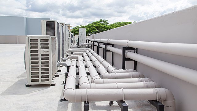 Technische Installation für Kälte- und Klimatechnik auf einem Dach Rohrleitungen und Klimageräte auf einem Flachdach zur Gebäudekühlung